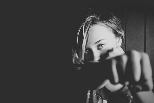Woman punching at the camera, showing resilience.