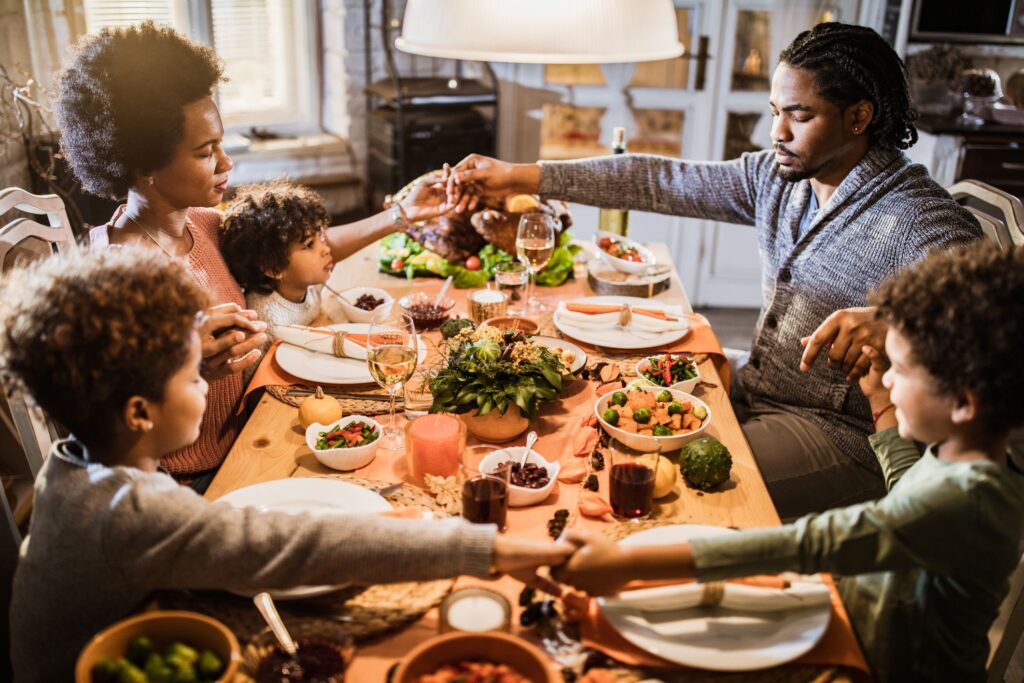 Family sitting around a table showing thankfulness and gratitude as they pray over the food.