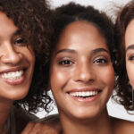 3 women smiling with natural makeup.